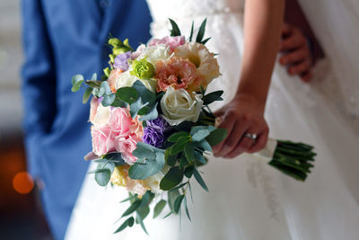 Midsection of bride holding bouquet