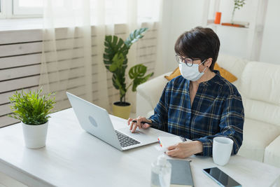 Side view of woman using laptop at table