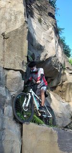 Full length of man with bicycle on rock