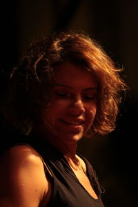 Close-up portrait of smiling woman against black background