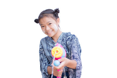 Portrait of happy girl playing with squirt gun against white background
