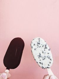 Close-up of hand holding ice cream against white background