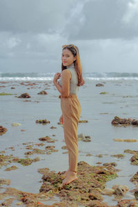 Full length of young woman standing on beach