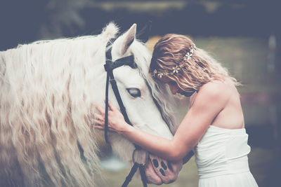 Young woman holding white horse