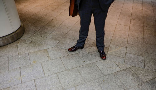 Low section of man standing on tiled floor