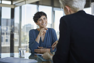 Two businesswomen talking at desk in office