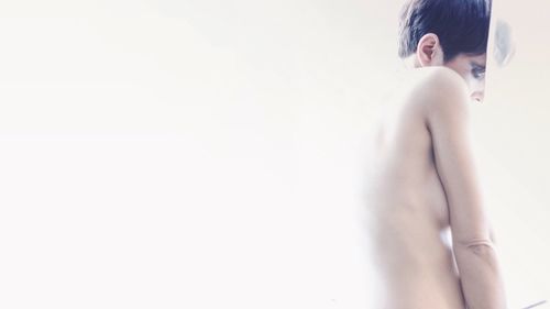 Side view of topless young woman against white background