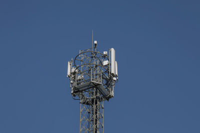 Low angle view of communications tower against clear blue sky