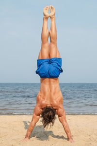 Man practicing handstand at beach