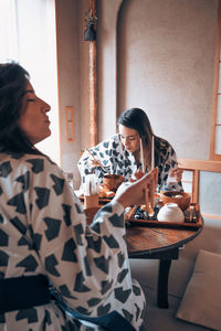 Side view of young woman sitting at home