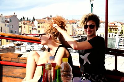 Young man and woman sitting on boat in city against sky