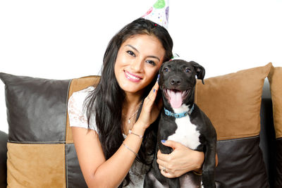 Portrait of smiling woman with dog sitting on sofa