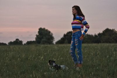 Woman with dog standing on field