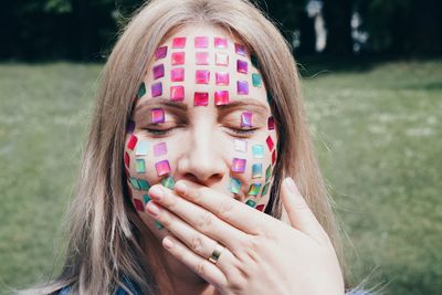 Close-up of young woman with colorful decorations on face at park