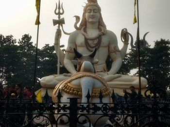 Low angle view of statue against trees and building