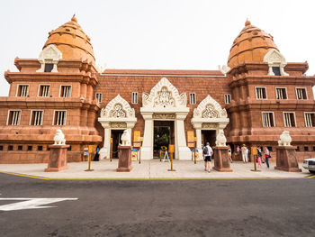 People outside temple against clear sky