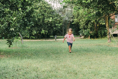 Full length of girl walking on grass against trees