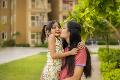 Mother kissing daughter outdoors