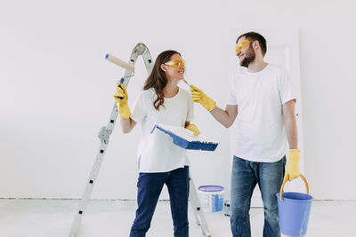 Happy smiling married couple engaged in renovation repair in the room of the house preparing to move