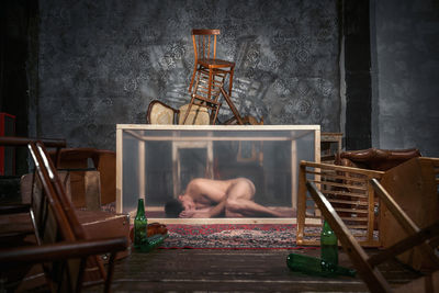 Naked mid adult man sleeping in container at home
