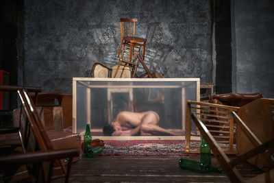 Man sitting on chair by table against wall