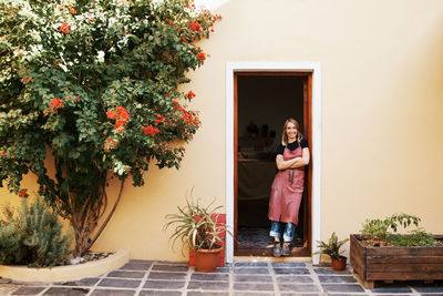 Woman standing by potted plant against wall