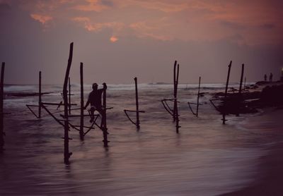 Silhouette man on beach against sky during sunset