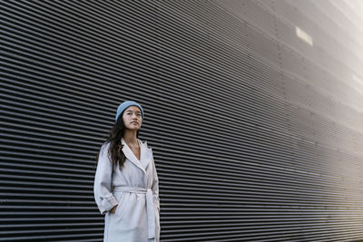 Thoughtful woman in front of black corrugated wall