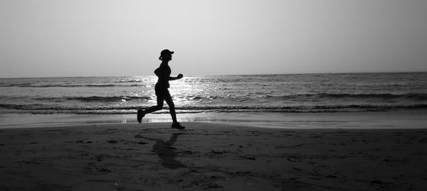 Silhouette man on beach against sky