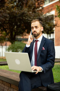 Businessman holding laptop talking on mobile phone