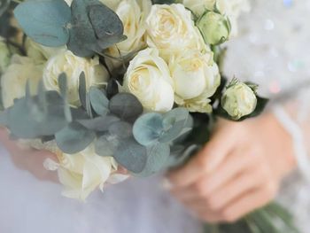 Midsection of bride holding bouquet