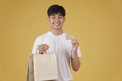 Portrait of smiling man standing against yellow background