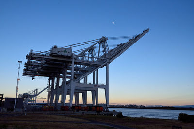 Crane by sea against clear blue sky