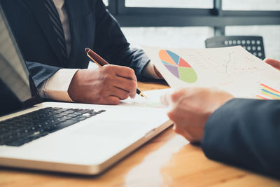Midsection of man holding paper at table