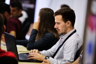 Side view of young man using laptop while sitting on chair