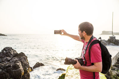 Man photographing at beach against clear sky