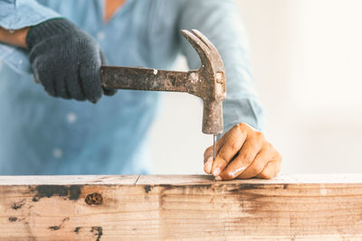 Midsection of man hammering nail on wood