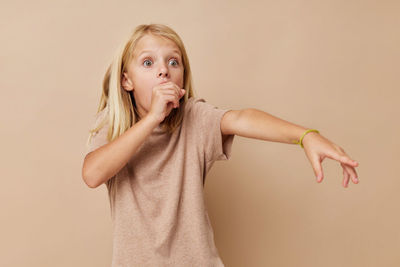 Portrait of young woman standing against wall