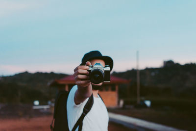 Man photographing with camera against clear sky