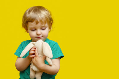 Portrait of boy eating lollipop against yellow background