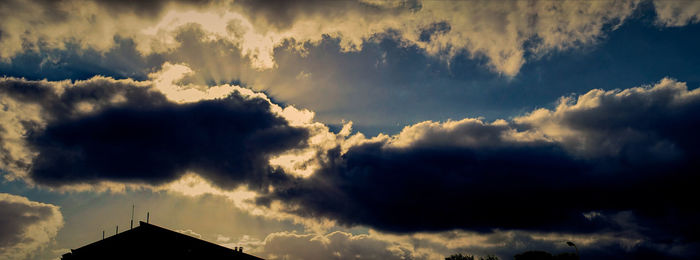 Low angle view of silhouette building against dramatic sky