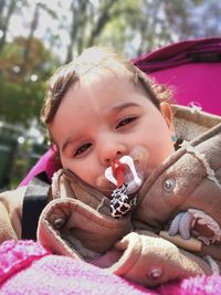 Close-up portrait of baby girl with pacifier in stroller