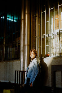 A young woman leaning on a wall while being lit by setting sun