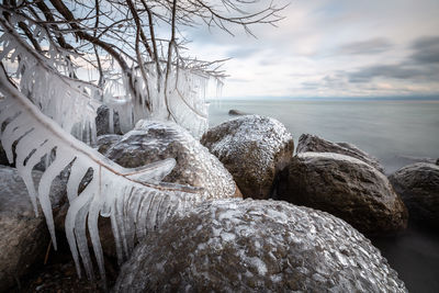 Rocks by sea against sky during winter