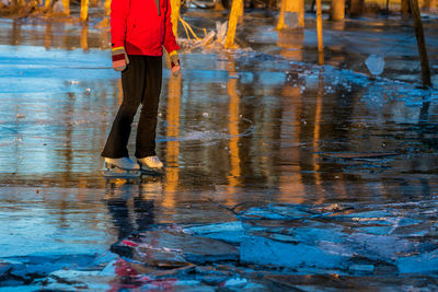 Low section of man standing on wet road during rainy season