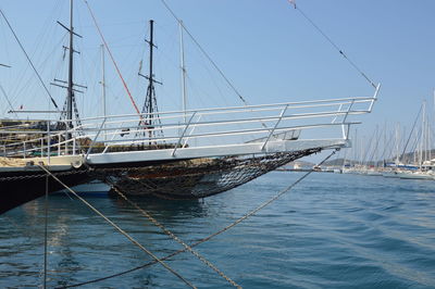 Sailboats moored in sea against clear blue sky