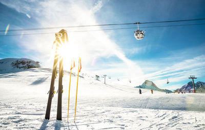 Ski lift over snow covered field against sky