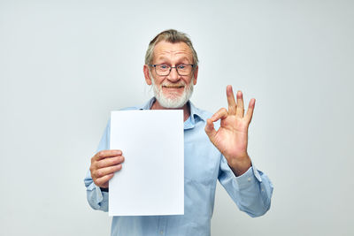 Midsection of man holding paper currency against white background