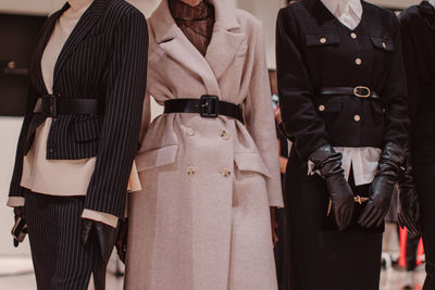 Fashionable details of a black classic outfits and a warm belted long beige coat.