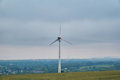 Wind turbines on field against sky